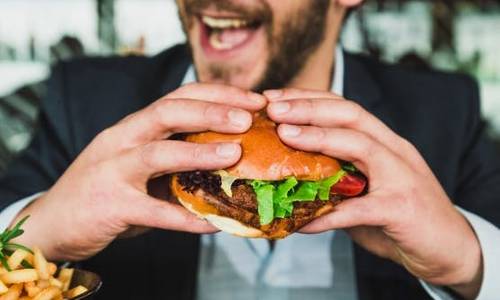 man about to bite into a burger